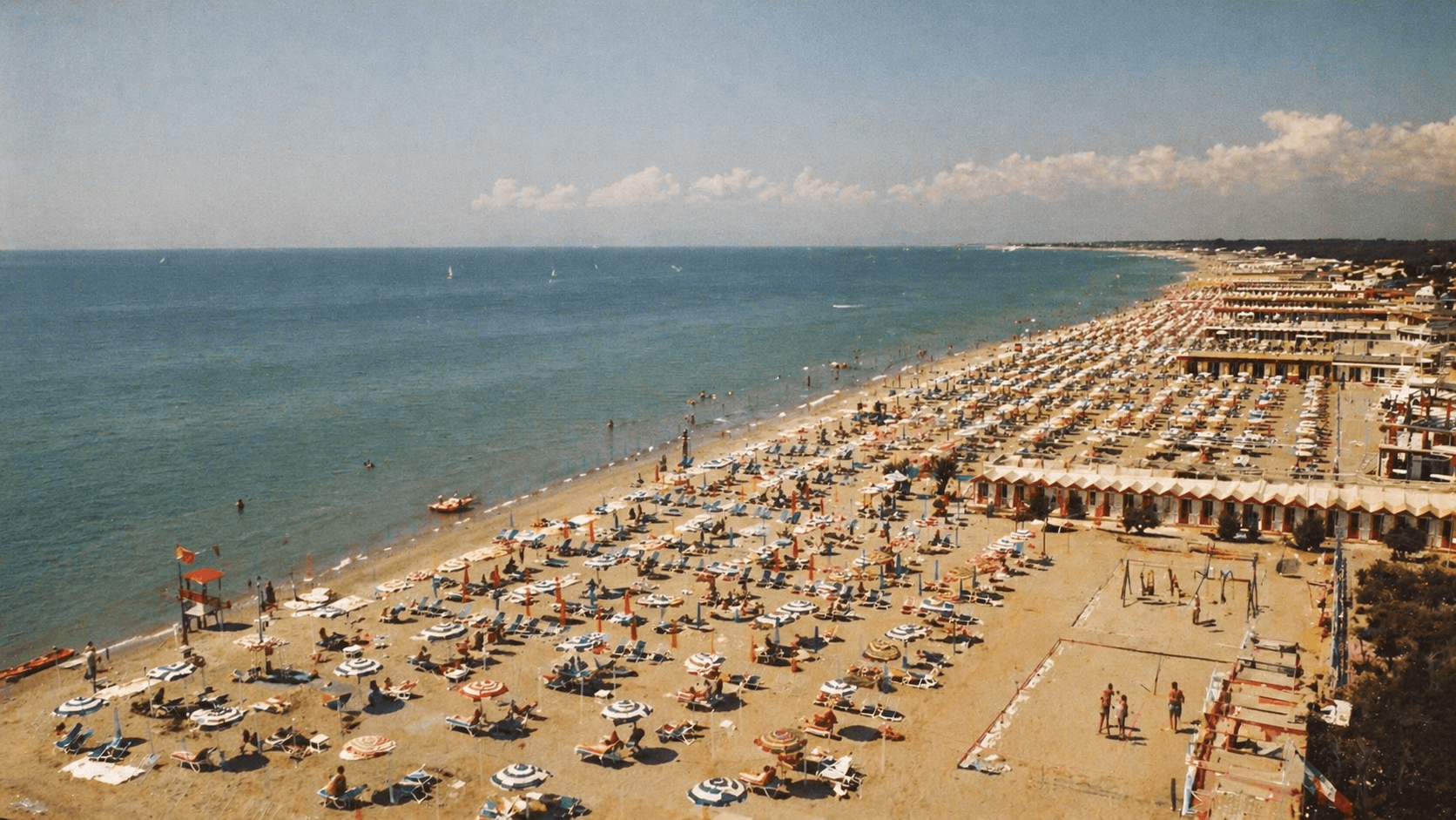 Panoramica aerea di stabilimenti balneari storici sul litorale italiano con ombrelloni e cabine